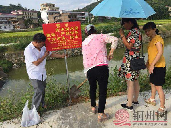 图为该校谭主任（男）正在与老师们悬挂安全警示牌）.jpg